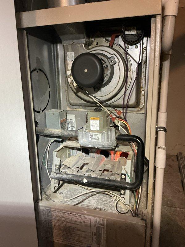 Performed comprehensive tune-up and city certification inspection on 24-year-old furnace system located in utility room. Conducted full system diagnostics including blower motor assembly inspection, gas valve operation verification, igniter and flame sensor testing, and electrical connection assessment. Also documented significant rust and corrosion on water heater tank top near copper pipe connections, indicating potential leak concerns that may require future attention. All furnace components found operational and system certified for continued use.