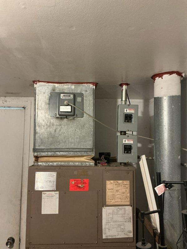 Completed furnace inspection on aging 1970s-era HVAC system located in interior closet room. Evaluated electric air handler unit with strip heat configuration, assessed electrical disconnect boxes, ductwork, and exterior wall-mounted components showing signs of age-related corrosion and rust on control panels and duct connections. Provided comprehensive replacement estimate for complete system upgrade due to equipment age and condition.