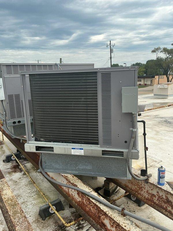 Completed commercial rooftop unit replacement, removing and recycling existing 5-ton RTU using crane with 28-ton boom capacity. Installed new Carrier 48TFEQ06A33A0A0A0 5-ton rooftop unit with A2L refrigerant safety classification on existing roof curb with fresh weatherstripping. Reused existing manual makeup air hood, converted electrical service from 3-phase to single-phase 208-230V/60Hz by replacing disconnect with junction box and GFI protection, performed full system testing and commissioning, and upgraded thermostat to White-Rodgers 1F95-0680 programmable unit. Unit carries 2-year parts and labor warranty coverage.