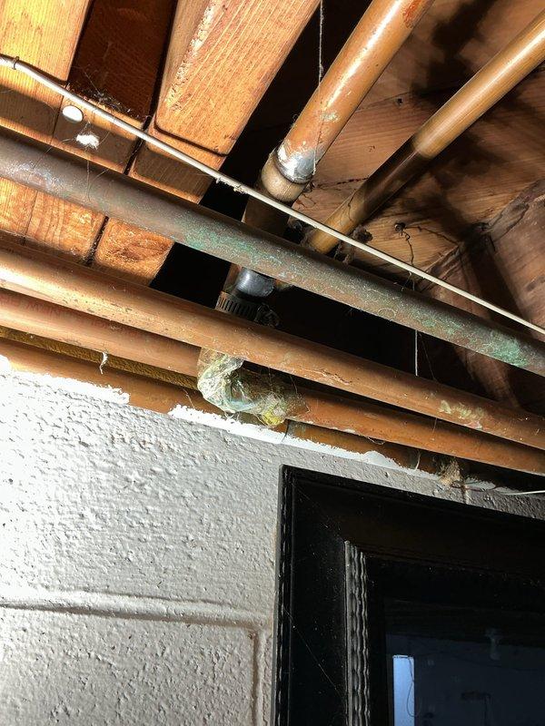 Responded to service call for basement pipe leak assessment following previous contractor's shutdown of basement access. Conducted thorough inspection of basement utility area, examining exposed copper gas lines, plumbing infrastructure, and mechanical systems throughout the space. Documented current condition of all visible piping, including vertical copper runs, valves, fittings, expansion tank, and pressure tank installations along cinder block walls. Inspected ceiling-mounted pipes running between floor joists, identifying copper and metal pipes requiring evaluation. Assessed basement accessibility and provided photographic documentation of existing plumbing system status to facilitate accurate estimate preparation for necessary repairs.