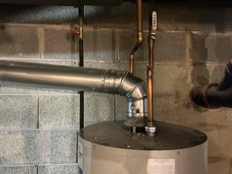 Returned to property for second violation correction on water heater flue installation. Previous repair was rejected by inspector due to improper use of elbow fitting in single-wall flue connector, which exceeded the 6-foot maximum allowable length. Corrected the flue connector configuration by removing the improvised elbow connection and installing compliant venting that meets code requirements for single-wall flue pipe length restrictions. Documented the corrected installation with photographs for inspector approval prior to leaving the premises.