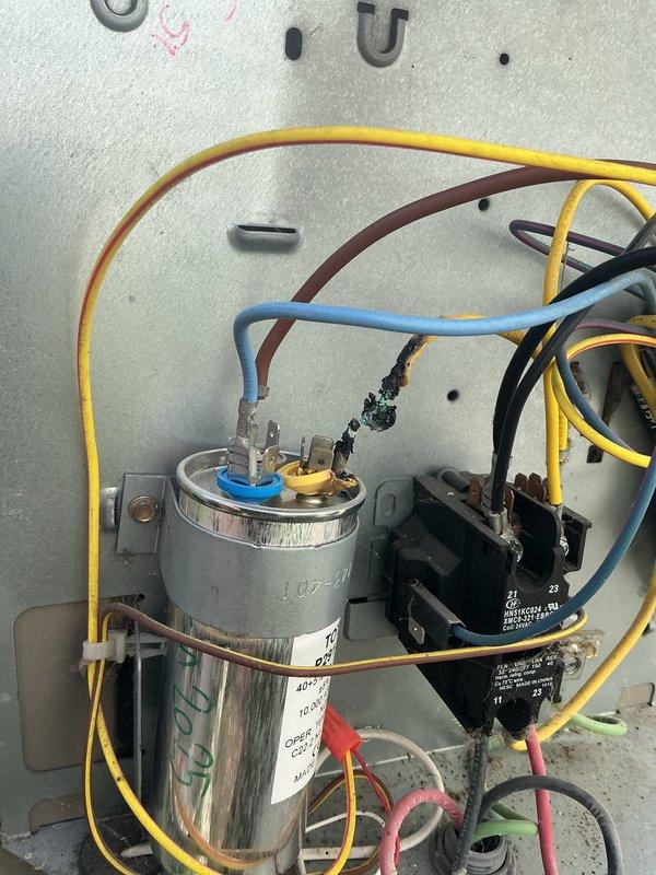 # HVAC Service Completed

Responded to a no cooling call on a 12-year-old residential air conditioning system. Upon arrival, performed diagnostic inspection of the outdoor condensing unit located on the rooftop. Visual inspection revealed burned and deteriorated wiring at the run capacitor connection point, with visible charring on the black wire terminal. The damaged wiring prevented proper electrical flow to the compressor and fan motor, resulting in system failure and loss of cooling capacity.

Disconnected power to the unit and removed the failed capacitor with compromised wire connections. Stripped back damaged wiring to clean copper, installed new run capacitor with proper microfarad rating for the system, and made secure electrical connections to the contactor and motor terminals using appropriate wire nuts and terminal connections. Verified all wire connections were tight and properly insulated.

Restored power to the unit and tested system operation. Confirmed compressor and c