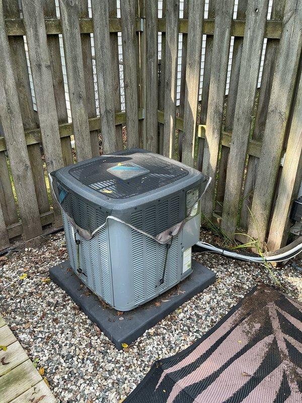 Responded to no cooling complaint on 7-year-old residential air conditioning system with non-operational outdoor compressor unit. Upon arrival, performed electrical diagnostics using clamp meter to verify voltage and amperage readings at the condenser unit located on gravel pad adjacent to residence. Customer had previously checked voltage and confirmed indoor furnace blower operation was functioning normally. Conducted comprehensive system evaluation including visual inspection of outdoor unit, electrical connections, and component functionality to determine root cause of compressor failure and restore cooling operation to the system.