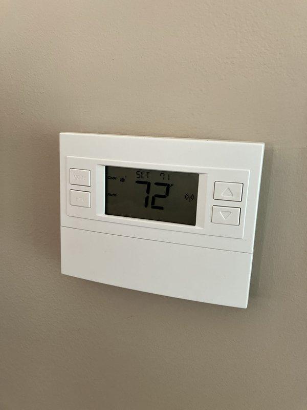 Performed equipment evaluation on 21-year-old air conditioning system located in basement to provide replacement estimate. Inspected existing furnace/air handler unit showing significant dust accumulation and operational wear, along with associated ductwork and electrical components. Assessed thermostat functionality, currently operating in cooling mode and maintaining proper temperature control at 71-72 degrees. Documented equipment condition through photographs and provided homeowner with comprehensive replacement options based on system age and current state of equipment.