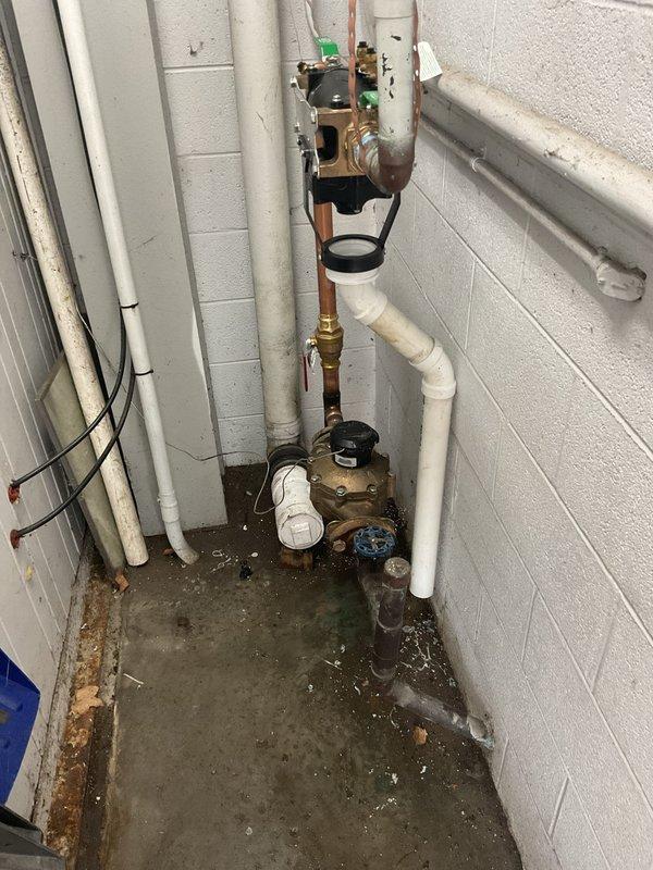 Installed reduced pressure zone (RPZ) backflow prevention assembly on commercial plumbing system per permit requirements requested 9/3. Assembly features brass fittings, test cocks, and green-handled isolation valves with copper and PEX piping connections mounted to wall in mechanical room, with white PVC drainage piping configured below the device.