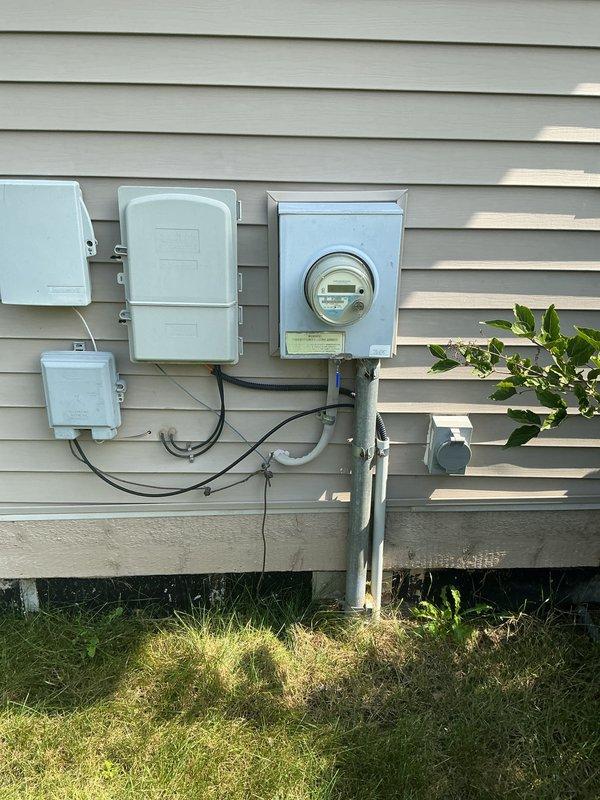 Completed comprehensive whole home electrical inspection for rental property. Evaluated exterior lighting fixture mounted on front wall, confirming proper installation and functionality of decorative lantern-style fixture with intact glazing and secure wall mounting. Inspected main electrical service equipment including meter base, digital electric meter, and exterior junction boxes with associated conduit runs, verifying proper grounding, secure connections, and code-compliant installation of all exterior electrical components.
