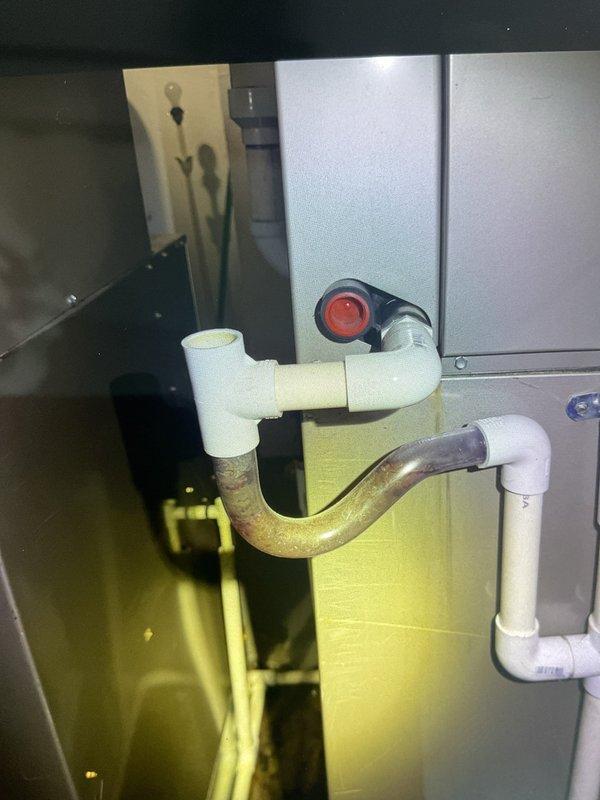 # Water Leak Resolution - 10-Year-Old AC System

Responded to service call for excessive water accumulation around basement HVAC system. Upon arrival, conducted thorough inspection of 10-year-old air conditioning unit and associated drainage components.

**Primary Issue Identified:**
Visual inspection revealed corroded and deteriorating brass condensate drain trap beneath the air handler. Significant oxidation and discoloration observed on metal piping connections, indicating prolonged exposure to moisture and potential failure points in the drainage system.

**Work Performed:**
- Inspected all condensate drain lines and connections from air handler to drainage point
- Examined internal air handler cabinet for signs of water intrusion or overflow
- Photographed corroded brass trap and PVC transition connections showing brown oxidation
- Assessed drain pan condition and primary/secondary drain line functionality
- Verified proper pitch and flow of condensate drainage system
- Checked fo