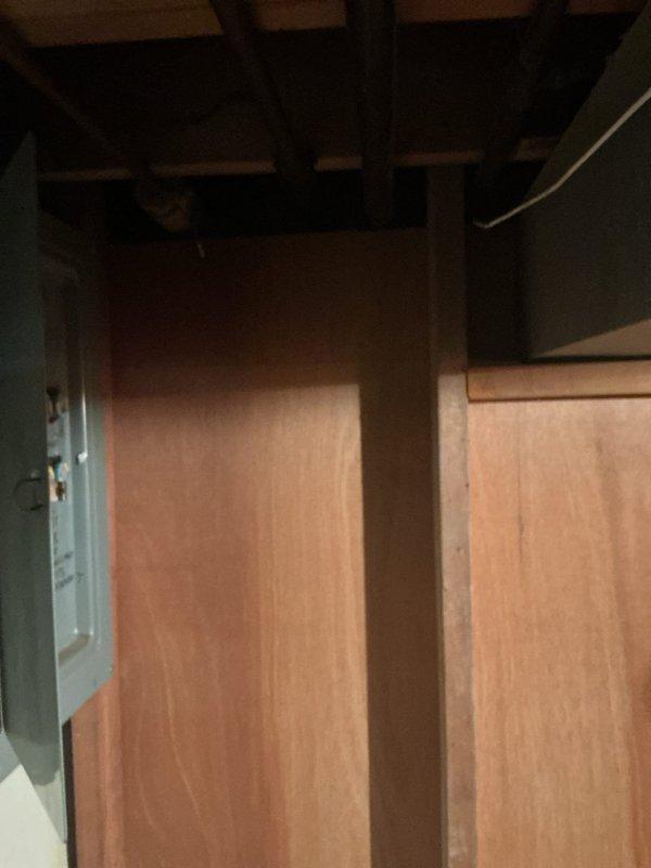 Responded to emergency call for damaged electrical service caused by fallen tree that displaced exterior electrical box from home. Assessed basement electrical panel located near furnace and water heater with less than 10 feet clearance. Panel showed functional interior components with multiple circuit knockouts and handwritten labeling system. Documented existing panel condition and clearance constraints for breaker box replacement requirements necessitated by exterior damage to main electrical service connection.