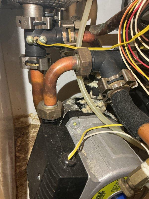Responded to service call for tankless water heater not heating efficiently. Upon inspection, found unit operational with no visible leaks present. Examined internal components, copper piping connections, and electrical wiring; all appeared in normal working condition with standard oxidation on copper lines. Verified gas supply lines, water inlet/outlet connections with red and blue valve handles, and PVC venting system properly secured. Inspected adjacent furnace and HVAC equipment in utility room to ensure no interference with tankless unit operation. Documented equipment condition with photographs showing proper installation and component arrangement. Unit tested and found functioning within normal parameters at time of service.