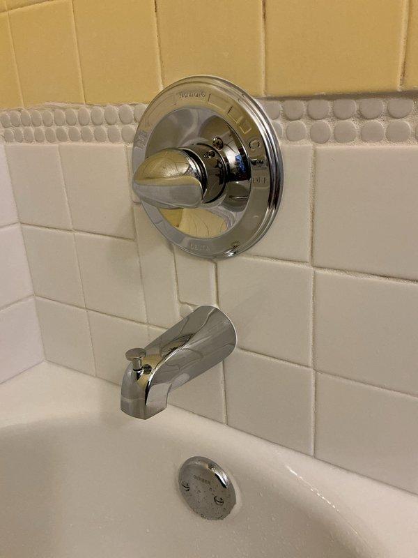 Completed return trip to connect valve from previous installation. Successfully installed and connected chrome-finished single-handle control valve and tub spout assembly on tiled bathroom wall. Verified proper water flow and operation of all fixtures.