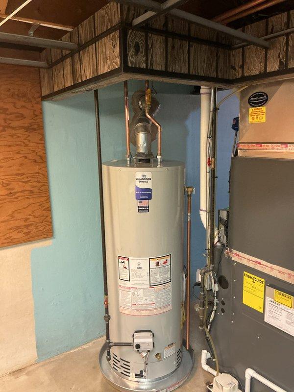 Completed installation of a new 50-gallon natural draft water heater in residential utility area. The existing non-functional unit was removed and replaced with a standard atmospheric vent water heater, including proper copper piping connections, temperature and pressure relief valve installation, and all necessary code-compliant fittings. All connections were tested and verified operational upon completion.