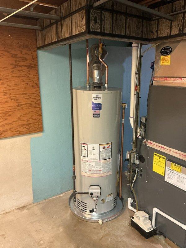 Completed installation of a new 50-gallon natural draft water heater in residential utility area. The existing non-functional unit was removed and replaced with a standard atmospheric vent water heater, including proper copper piping connections, temperature and pressure relief valve installation, and all necessary code-compliant fittings. All connections were tested and verified operational upon completion.