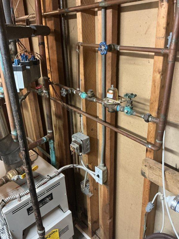 # Plumbing Service - Whole Home Inspection

## Primary Concern Addressed

Responded to complaint of hot water emitting sulfur/rotten egg odor. Inspected Bradford White 40-gallon natural gas water heater (Model RG240T6N, 40,000 BTU/hr input) and identified odor as likely caused by sulfur bacteria reaction with magnesium anode rod in tank. 

## Water Heater Inspection Findings

Examined water heater specifications and operational components. Unit displayed proper manufacturer labeling with all safety warnings intact. Verified gas input specifications and clearance requirements met code standards. Documented existing condition of tank exterior and label placement for service records.

## Whole Home Plumbing System Inspection

Conducted comprehensive inspection of residential plumbing infrastructure. Examined exposed copper supply lines running vertically and horizontally through wall cavity between framing studs. Inspected multiple shut-off valves throughout system, including turquoise an