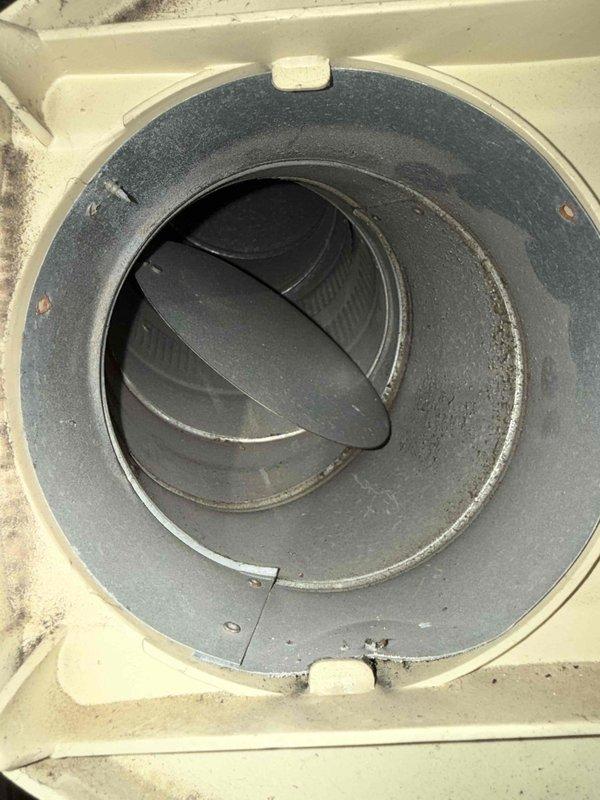 Responded to no cooling complaint on 19-year-old residential air conditioning system with outdoor condenser unit located in backyard and evaporator coil in basement. Performed diagnostic inspection of system components including condenser unit, refrigerant lines, and airflow controls. Documented equipment condition with photographs showing weathered outdoor unit with protective cover and basement damper assembly with visible dust accumulation on blades and mounting frame. System evaluated for age-related wear and operational efficiency given equipment has exceeded typical service life expectancy.