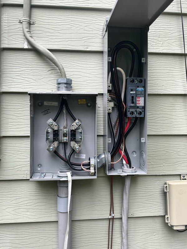 Completed electrical warranty service to relocate main service panel. Removed existing interior-mounted electrical panel from basement area and reinstalled exterior-mounted service equipment on building's exterior wall. Installed new dual meter base enclosure with proper conduit routing, including curved service entrance conduit from overhead connection. Mounted new main breaker panel adjacent to meter base with appropriate circuit breaker configuration and wire terminations. Ran gray PVC conduit from panels downward along exterior siding with proper mounting brackets and support. Relocated junction box and associated wiring in basement area, securing all conductors to floor joists with appropriate support methods. Verified all electrical connections, torqued terminals to manufacturer specifications, and confirmed proper operation of all circuits and overcurrent protection devices.