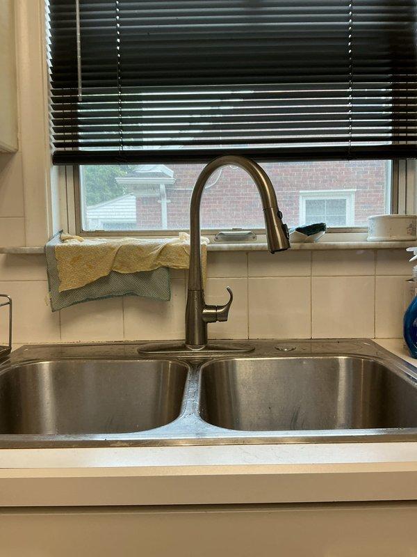 Responded to service call for multiple drain cleaning and kitchen faucet replacement. Successfully cleared 3-4 clogged drains throughout the residence to restore proper drainage flow. Removed existing kitchen faucet and installed new brushed nickel pull-down faucet unit at double-basin stainless steel sink. Inspected under-sink plumbing connections, including PVC P-trap configuration, to ensure proper operation and verify no leaks present. Tested all cleared drains and new faucet installation for proper function before completing service.