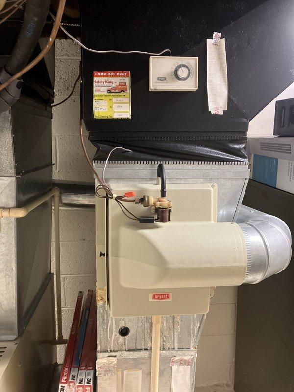 Completed comprehensive inspection and full system estimate for 26-year-old furnace located in basement. Evaluated existing Bryant humidifier unit, ductwork configuration, control systems, and thermostat operation. Assessed outdoor condensing unit condition with protective cover in place on gravel pad adjacent to foundation. Documented all system components including electrical connections, duct insulation, and overall equipment condition to provide complete replacement recommendations for aging HVAC system.