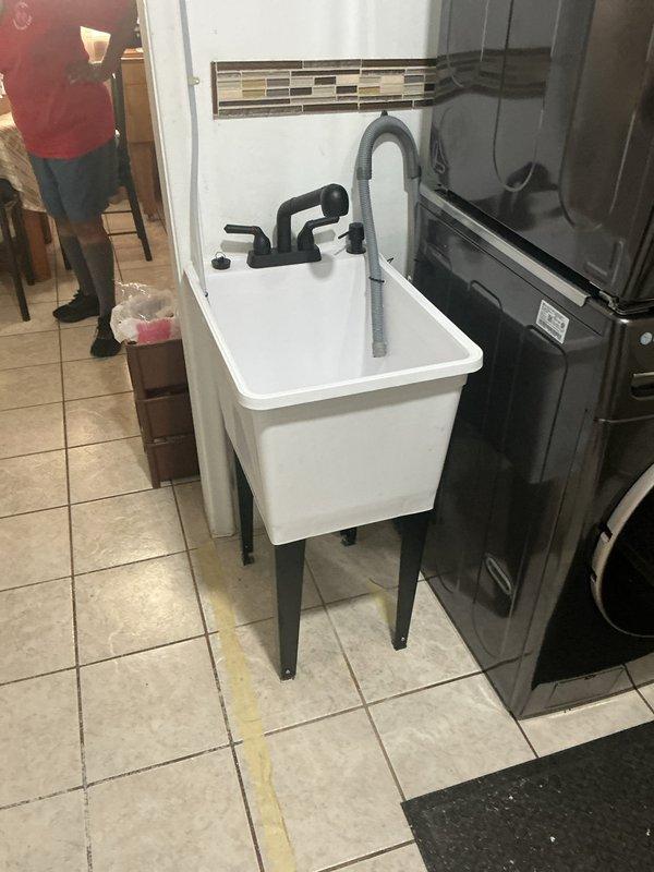 Completed on-site assessment of plumbing configuration conflict where existing water supply lines and PVC drain connections protruding from floor were preventing relocation of stackable washer/dryer unit that was blocking side door access. Evaluated current utility sink installation with existing copper water supply lines, braided flex connectors, and floor-mounted P-trap assembly. Provided professional recommendations for reconfiguring water supply and drain piping to allow appliance repositioning while maintaining functionality of utility sink, including options for relocating stub-outs and drain connections to accommodate both fixtures in desired layout.