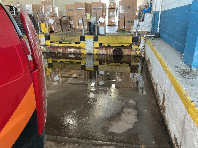 Completed sump pump installation at commercial loading dock facility experiencing significant water accumulation. Installed new sump pump system in concrete basin with deteriorated walls showing extensive water damage and rust staining. Routed discharge line through flooded area to manage standing water conditions throughout the loading bay and warehouse space.