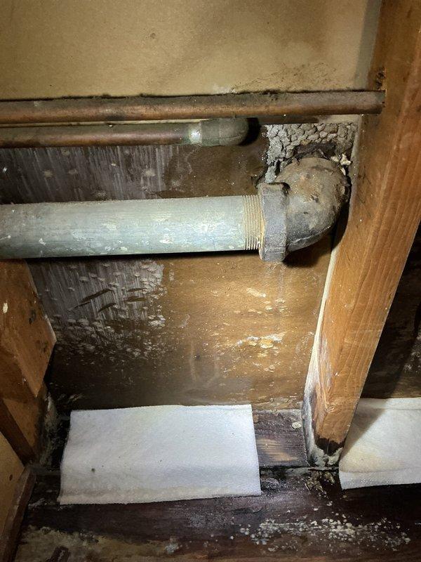 Responded to active water leak dripping from bedroom ceiling light fixture onto bed. Traced leak source to deteriorated plumbing fitting in second-floor bathroom directly above affected bedroom. Upon investigation, identified compromised pipe connection with visible corrosion on copper supply line and deteriorated PVC piping showing weathered surfaces and rough texturing. Repaired faulty fitting, secured all connections, and verified water supply system integrity. Leak has been stopped at the source. Customer advised that ceiling and electrical fixture may require separate repair due to water intrusion damage.