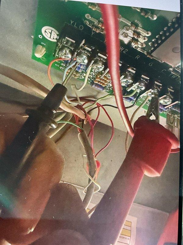 Responded to no cooling complaint on 4-year-old attic-mounted air conditioning system blowing hot air. Upon inspection, accessed control board and wiring assembly within air handler. Diagnosed failed control board based on visual inspection of PCB components and wire connections. Documented existing wiring configuration showing multiple wire connections to circuit board including thermostat wiring, power connections, and component control wires. Control board exhibited signs of failure requiring replacement to restore cooling operation.