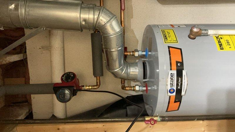 Responded to service call regarding water heater tank leak at side joint connection. Upon inspection, identified active leak at threaded pipe joint on water heater assembly. Documented existing installation configuration including dual water heater setup with associated copper supply lines, galvanized vent piping, pressure relief valve, and shut-off valves. Captured photographic evidence of leak location and overall system condition for warranty recall documentation. Customer advised to contact manufacturer customer service line for recall verification and resolution procedures.