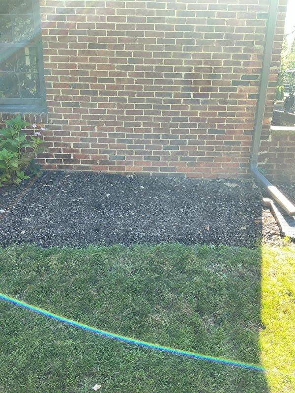 Conducted on-site evaluation for whole home generator installation. Assessed potential installation location along side yard of brick residential structure, photographing existing landscape conditions including garden beds with hydrangeas and available clearance areas. Documented prepared mulched area adjacent to brick wall that provides suitable access for generator placement, noting proximity to existing electrical service and adequate setback from structure. Evaluated site conditions including drainage considerations, accessibility for equipment delivery and installation, and compliance requirements for residential standby generator systems. Provided comprehensive estimate for complete whole home automatic standby generator system including unit sizing, transfer switch installation, and necessary electrical connections.