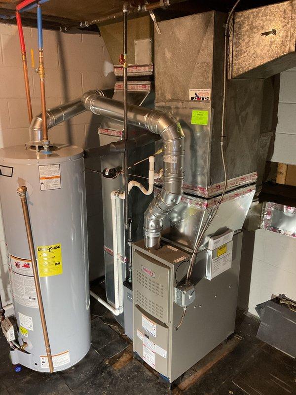 Completed full furnace installation in basement mechanical room. Installed new Lennox furnace unit with complete metallic ductwork configuration, including curved and straight sections with proper joints and connections. Routed silver galvanized ductwork from furnace to distribution points with appropriate elbow fittings. Connected air handler/evaporator coil unit with copper refrigerant lines and brass fittings. Installed gas shut-off valve and made all necessary gas line connections. Verified proper clearances around existing AO Smith water heater and coordinated all mechanical, electrical, and gas connections per code requirements. All ductwork secured and sealed, system tested for proper operation and airflow.