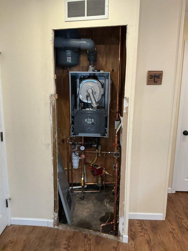 Completed full commercial boiler installation over two-day period, including mechanical and electrical connections, gas piping modifications, and venting system with liner. Installed wall-mounted condensing boiler unit in recessed cavity with PVC vent piping, configured copper supply and return lines with isolation valves and pressure gauges, and integrated expansion tank into hydronic system. Reconnected all utilities, tested system operation, and verified proper combustion and venting performance upon completion.