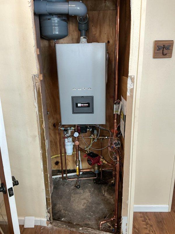 Completed full commercial boiler installation over two-day period, including mechanical and electrical connections, gas piping modifications, and venting system with liner. Installed wall-mounted condensing boiler unit in recessed cavity with PVC vent piping, configured copper supply and return lines with isolation valves and pressure gauges, and integrated expansion tank into hydronic system. Reconnected all utilities, tested system operation, and verified proper combustion and venting performance upon completion.