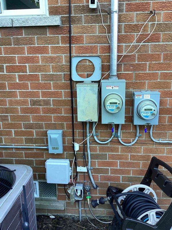 Conducted on-site evaluation for new whole home generator installation at manufactured home. Assessed existing electrical service infrastructure including main meter assembly, panel configuration, and available mounting locations on exterior brick wall. Documented current electrical setup with multiple meter boxes, conduit routing, and service disconnect components to determine optimal generator placement and necessary electrical connections for seamless integration with existing system.