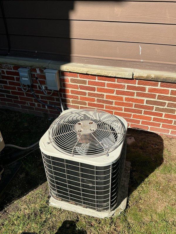 Responded to service call for reported condenser leak at upstairs unit. Upon arrival, performed visual inspection of outdoor condenser unit and indoor thermostat system. Assessed 10-15 year old HVAC system for potential drip pan failure and evaluated overall unit condition. Documented equipment with photos showing exterior condenser placement and indoor White-Rodgers programmable thermostat displaying current temperature reading of 83 degrees.