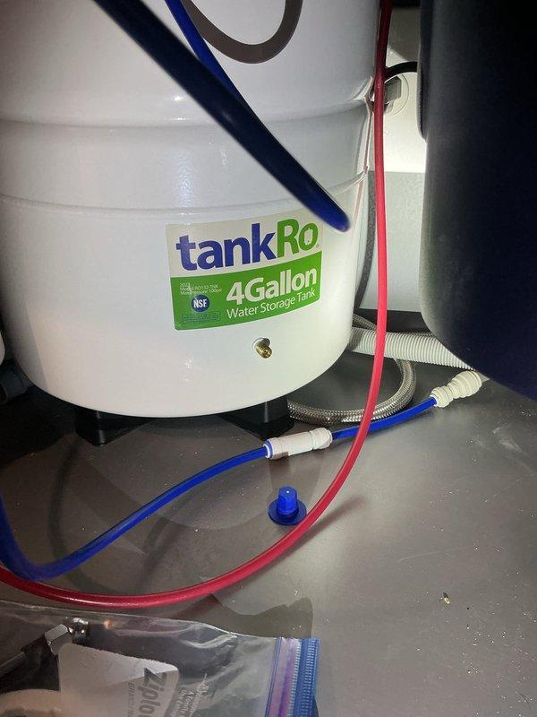 Responded to service call for reverse osmosis system not filling storage tank after filter replacement. Upon inspection, found 4-gallon tankRO storage tank with improperly connected supply lines and potential air-lock issue preventing tank fill. Verified proper connection of blue feed line, red output line, and drain line connections. Checked automatic shut-off valve operation and cleared air from system to restore proper water flow and tank filling functionality. System tested and confirmed operational upon completion.