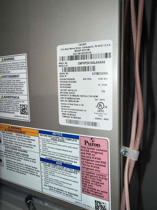 Responded to water leak complaint in main floor closet housing HVAC equipment and water heater. Upon inspection, identified unit as Goodman CNPVP24H4LAAAAA system manufactured in 2018 utilizing R-410A refrigerant. Examined control board, wiring connections, and condensate drainage system to locate source of moisture intrusion. Documented equipment condition and control board configuration for diagnostic purposes.