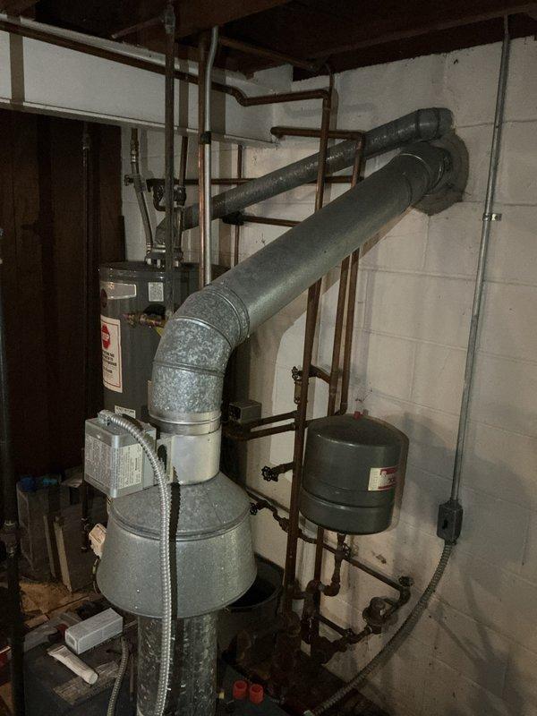 Conducted estimate on 35-40 year old Weil-McLain hot water boiler in basement that failed to provide adequate heating during previous winter season. Upon inspection, found extensive corrosion on piping system, water damage on concrete floor indicating previous leaks or flooding, and aging expansion tank with deteriorated connections. Documented existing mechanical room conditions including corroded brown piping, rusted fittings throughout the hydronic system, and overall equipment deterioration consistent with age and moisture exposure, then provided replacement recommendations for complete boiler system upgrade.