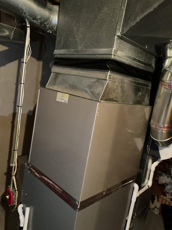 Responded to customer complaint of air conditioning system blowing warm air. Evaluated 10+ year old cooling equipment located in basement, including air handler with finned coil assembly and associated ductwork connections. Inspected furnace/air handler unit, condensate drainage system with PVC piping, flexible and rigid ductwork transitions, and electrical connections. Documented existing HVAC system configuration and equipment condition through detailed assessment. Provided comprehensive replacement estimate for cooling system and recommended surge protector installation to protect new equipment from electrical damage.