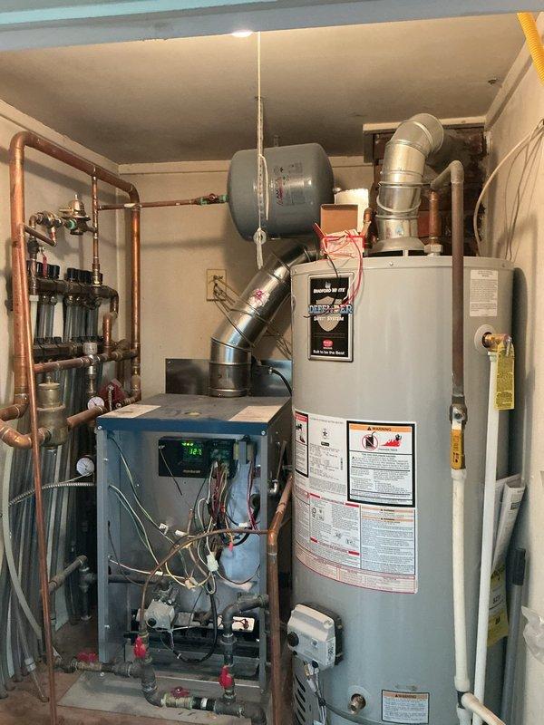 Completed comprehensive Gold boiler inspection on 3-year-old residential heating system located in garage. Performed full system evaluation including visual inspection of internal components with access panel removed, verified proper operation of control board and digital display, checked all electrical connections and wiring, inspected gas lines and copper piping connections, tested safety shut-off valves, examined ductwork and venting system, and assessed expansion tank mounting. Inspected associated water heater and plumbing manifold system with multiple zone valves. All components found to be operating within normal parameters with no immediate service needs identified. Documentation photos captured for maintenance records.