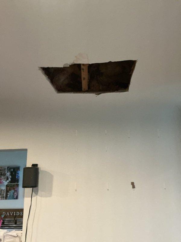 Responded to service call for ceiling damage investigation and potential water leak detection. Upon arrival, inspected existing ceiling hole with visible water staining, discoloration, and deteriorated drywall material indicating moisture infiltration. Expanded access opening to expose plumbing lines and structural framing for thorough leak assessment. Examined visible piping, wooden framing members, and cavity space above ceiling for active leaks, moisture accumulation, and source of water damage. Documented conditions with photographic evidence showing extent of ceiling deterioration and compromised building materials.