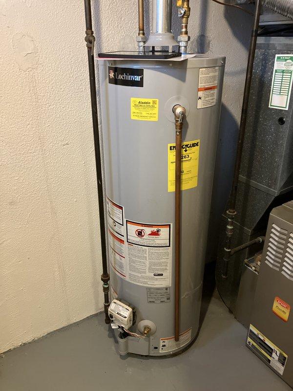 Conducted comprehensive assessment of existing basement HVAC system for replacement estimate on small residential property under 1500 square feet. Evaluated current electric heat pump system including air handler unit mounted in basement mechanical room with existing ductwork configuration. Documented equipment specifications, installation conditions, and spatial requirements for replacement system. Assessed metallic supply ductwork runs, flexible duct connections, and overall distribution system integrity. Photographed existing HVAC equipment showing gray metal air handler with visible manufacturer labels and warning placards, along with adjacent water heater and plumbing infrastructure. Evaluated basement installation environment including exposed ceiling joists, reflective insulation on walls, structural framing, and available clearances for new equipment installation. Prepared technical documentation and recommendations for complete heating and cooling system replacement compatible