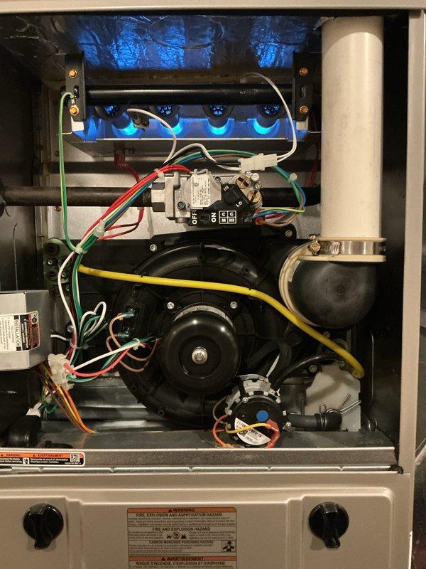Completed comprehensive Gold-level furnace inspection and tune-up on a 4-year-old unit located in basement. Performed full system evaluation including burner assembly inspection with flames burning clean and blue, indicating proper combustion and air-fuel mixture. Verified gas valve operation and all electrical connections secure with proper wire routing. Inspected blower motor assembly and confirmed operational integrity. Checked UV light system functioning correctly in upper cabinet section. Examined all control components, safety switches, and wiring harnesses for wear or damage. Verified condensate drainage system clear and PVC vent piping secure. Confirmed all manufacturer labels and warning decals present and legible. System operating within normal parameters with no deficiencies noted. Unit maintained preventive maintenance schedule and remains in good working condition with no repairs required at this time.