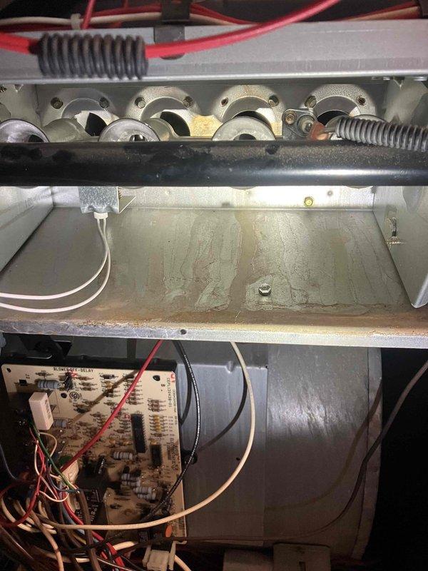 Responded to no-heat call on 10+ year old furnace located in basement. Upon inspection, found unit failing to ignite due to corroded and deteriorated control board and burner assembly. Evidence of prolonged moisture exposure was visible throughout the unit, with extensive rust staining on the metal base and water damage affecting electrical components. Control board showed signs of environmental degradation with multiple colored wire connections compromised by corrosion. Burner ports and heat exchanger displayed significant age-related wear and residue buildup. Documented existing conditions with photos showing circuit board deterioration, corroded metal surfaces, and compromised burner assembly. Advised homeowner of findings and provided recommendations for necessary repairs or replacement given the age and condition of the equipment.