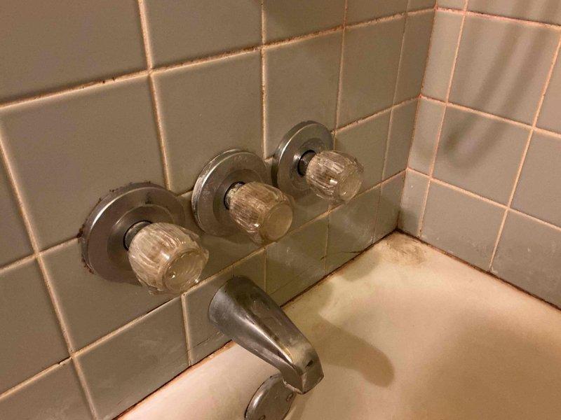 Responded to service call for two plumbing issues in residential property. Addressed dripping bathtub faucet in upstairs bathroom where previous DIY repair with aftermarket hardware store parts had failed. Inspected three-handle chrome shower/tub valve assembly mounted on ceramic tile wall. Disassembled faucet controls, replaced worn cartridges and seals with manufacturer-specified components to restore proper shut-off function and eliminate persistent drip from tub spout.

Proceeded to basement with family member assistance to access second issue. Inspected main water shut-off valve showing active leak at valve stem. Brass gate valve displayed corrosion and mineral deposits consistent with age-related deterioration. Tightened packing nut and replaced packing material to stop leak at valve stem. Tested valve operation to ensure proper function for emergency shut-off capability. Both repairs completed successfully with no active drips remaining at time of departure.
