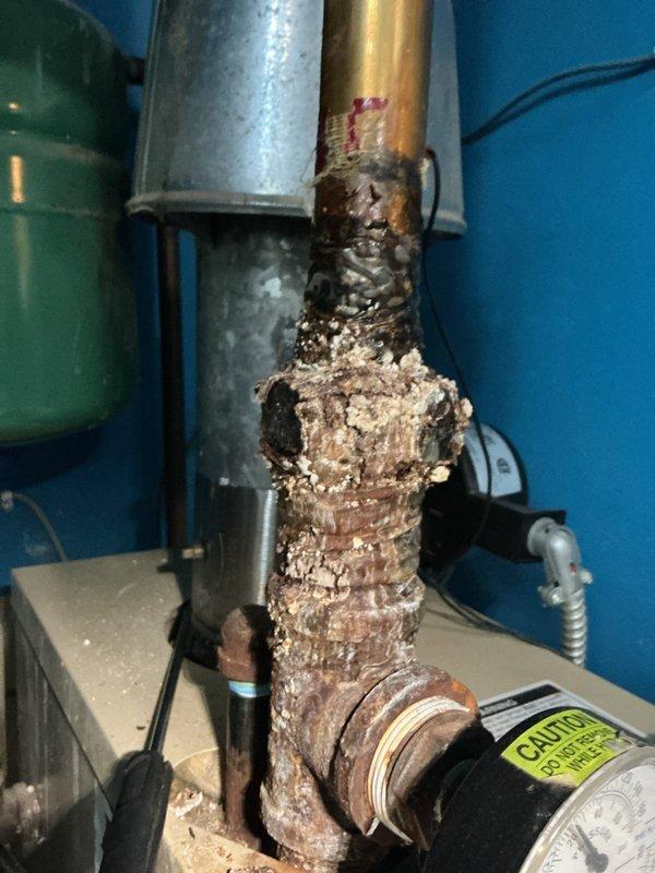 Completed comprehensive Gold-level maintenance inspection on residential boiler system (circa 2007) located in main floor utility room. Inspected all internal components including blower motor assembly, gas valve connections, electrical wiring, control modules, and safety systems; all mechanical and electrical components found operating within normal parameters. Identified significant corrosion and heavy mineral deposit buildup on vertical copper supply piping, indicating active or previous water leakage that requires attention to prevent system failure; recommended pipe replacement to address deterioration before compromising system integrity.