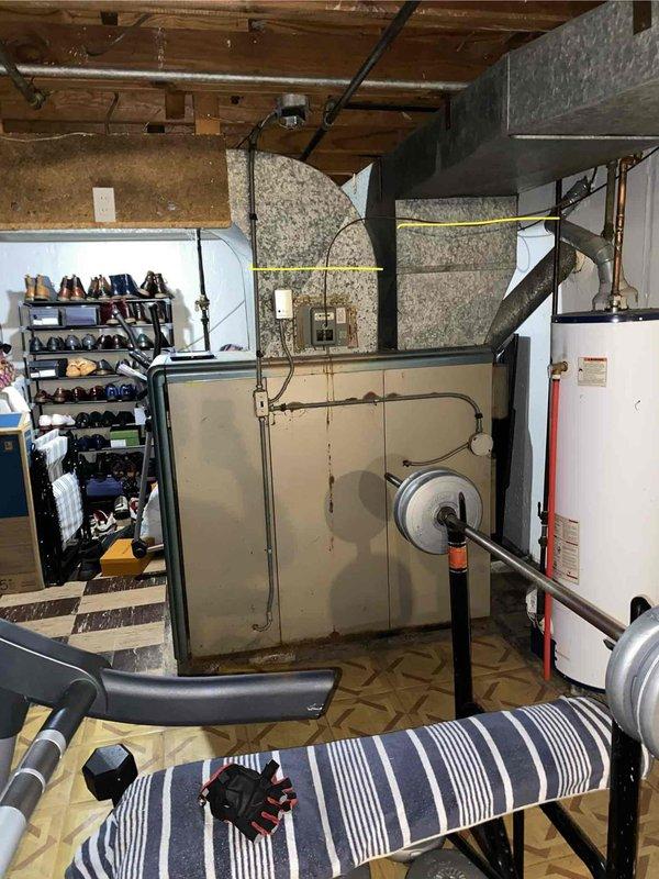Performed comprehensive inspection of 10+ year old Lux brand forced air furnace system located in basement. Evaluated existing heating equipment condition, noting significant age-related wear on unit cabinet and connected ductwork with visible surface corrosion and discoloration on galvanized metal components. Assessed gas line connections, ductwork integrity, and overall system performance to provide replacement estimate recommendations for aging HVAC equipment.