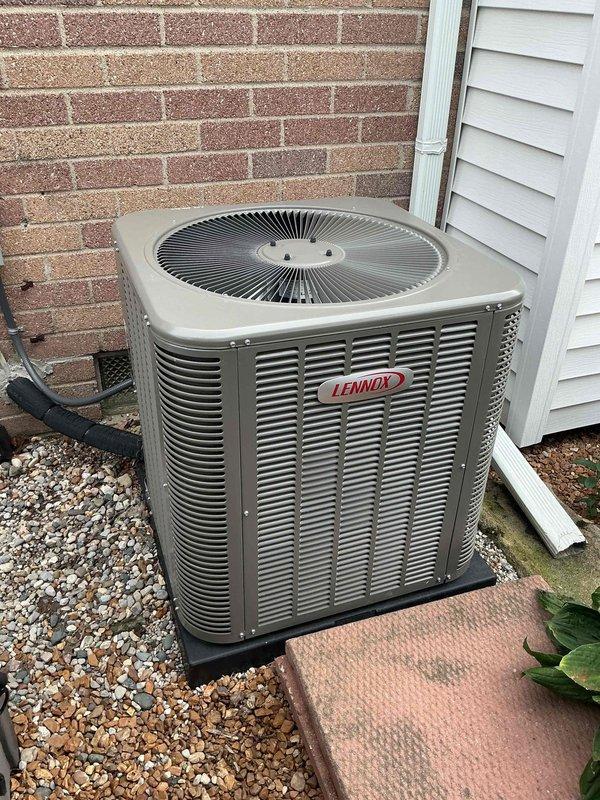 Completed comprehensive Gold-level maintenance inspection on residential multi-unit HVAC system including 2-6 year old gas furnace located in basement and Lennox outdoor air conditioning condenser unit. Verified proper furnace operation with blue flame combustion pattern indicating optimal gas-air mixture, inspected gas valve assembly and electrical connections, and confirmed blower motor functionality. Exterior AC unit inspection revealed clean condenser coils, proper gravel drainage base, secure electrical conduit connections, and overall good equipment condition with no visible damage or deterioration.
