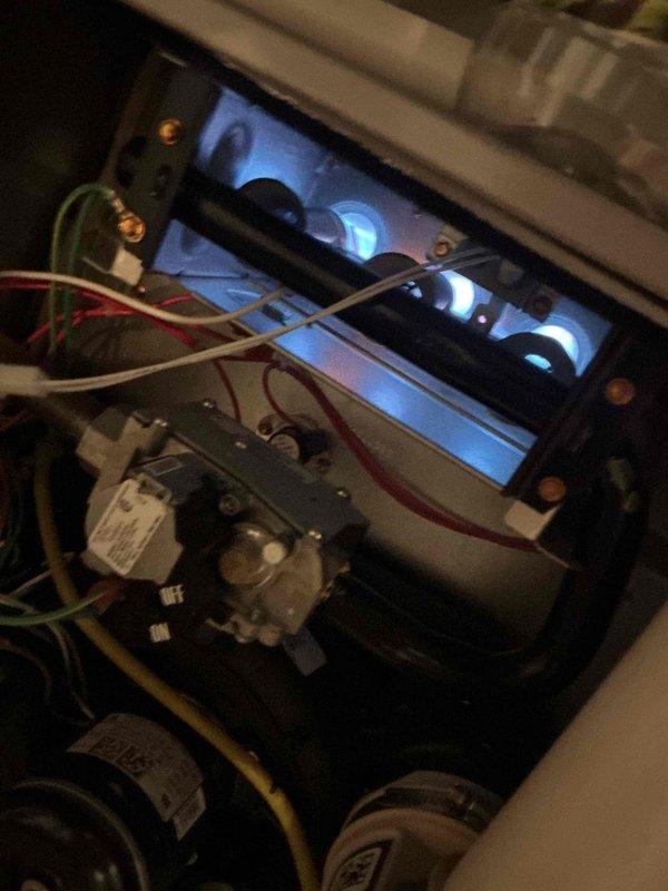 Completed comprehensive Gold-level maintenance inspection on residential multi-unit HVAC system including 2-6 year old gas furnace located in basement and Lennox outdoor air conditioning condenser unit. Verified proper furnace operation with blue flame combustion pattern indicating optimal gas-air mixture, inspected gas valve assembly and electrical connections, and confirmed blower motor functionality. Exterior AC unit inspection revealed clean condenser coils, proper gravel drainage base, secure electrical conduit connections, and overall good equipment condition with no visible damage or deterioration.