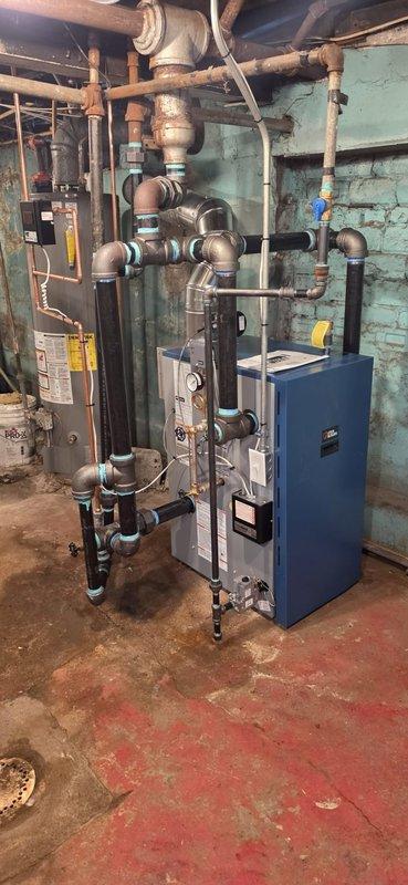 Completed boiler installation in basement mechanical room, including all necessary piping connections and system integration with existing infrastructure. Mechanical and electrical permits were requested and approved for the installation. Connected new blue-cased boiler unit to copper and metal piping network, ensuring proper gas line routing and secure mounting. System was tested and reconnected to verify operational functionality upon completion.