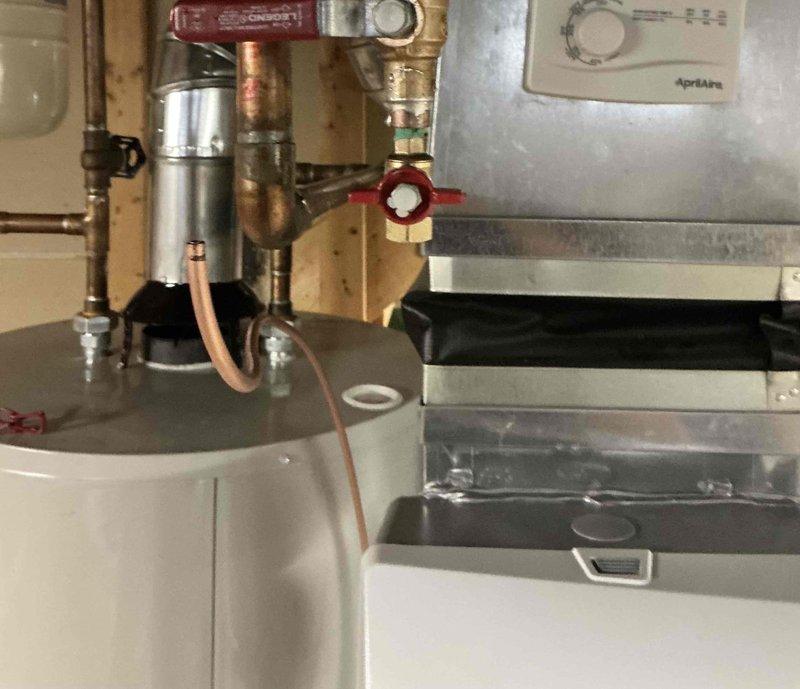 Installed Aprilaire 600M bypass humidifier system in residential basement mechanical room. Unit was mounted adjacent to existing furnace with proper electrical and water supply connections, including copper piping with shutoff valve and drain line installation to integrate with the forced air heating system.