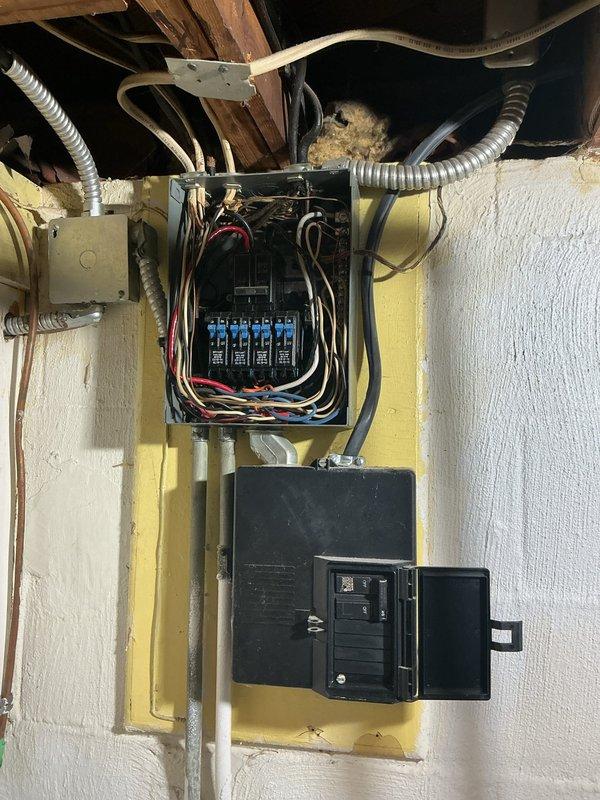 Responded to service call for flickering lights and aging electrical panel. Upon inspection, discovered severely corroded exterior service entrance with deteriorated weatherhead and compromised conduit connections showing extensive rust damage. Interior panels revealed animal nesting material contamination in upper breaker box, creating potential fire hazard and contributing to intermittent electrical issues. Cleaned debris from panel enclosure, inspected all breaker connections and bus bars for signs of overheating or loose connections. Documented multiple code violations including improper wire management and inadequate weather protection at service entrance. Recommended immediate replacement of exterior weatherhead assembly and service entrance components due to safety concerns. Advised scheduling complete panel upgrade to address aging infrastructure, eliminate flickering issues, and bring installation up to current electrical code standards.