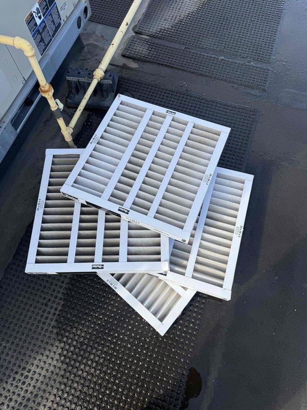 Performed scheduled filter change on commercial rooftop unit (RTU). Accessed roof-mounted packaged HVAC system and removed four heavily soiled pleated air filters showing significant dust accumulation and discoloration. Installed new replacement filters to restore proper airflow and system efficiency. Unit operational upon completion of service.